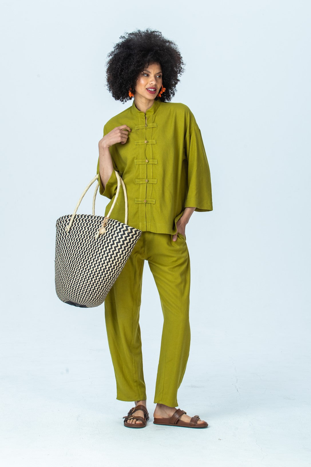 Parker chartreuse barrel pants, full length with hand at collar, looking to the side, styled with the Kinsley