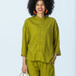 Kinsley chartreuse kaftan-style shirt, front view with hand in pocket, holding a woven basket