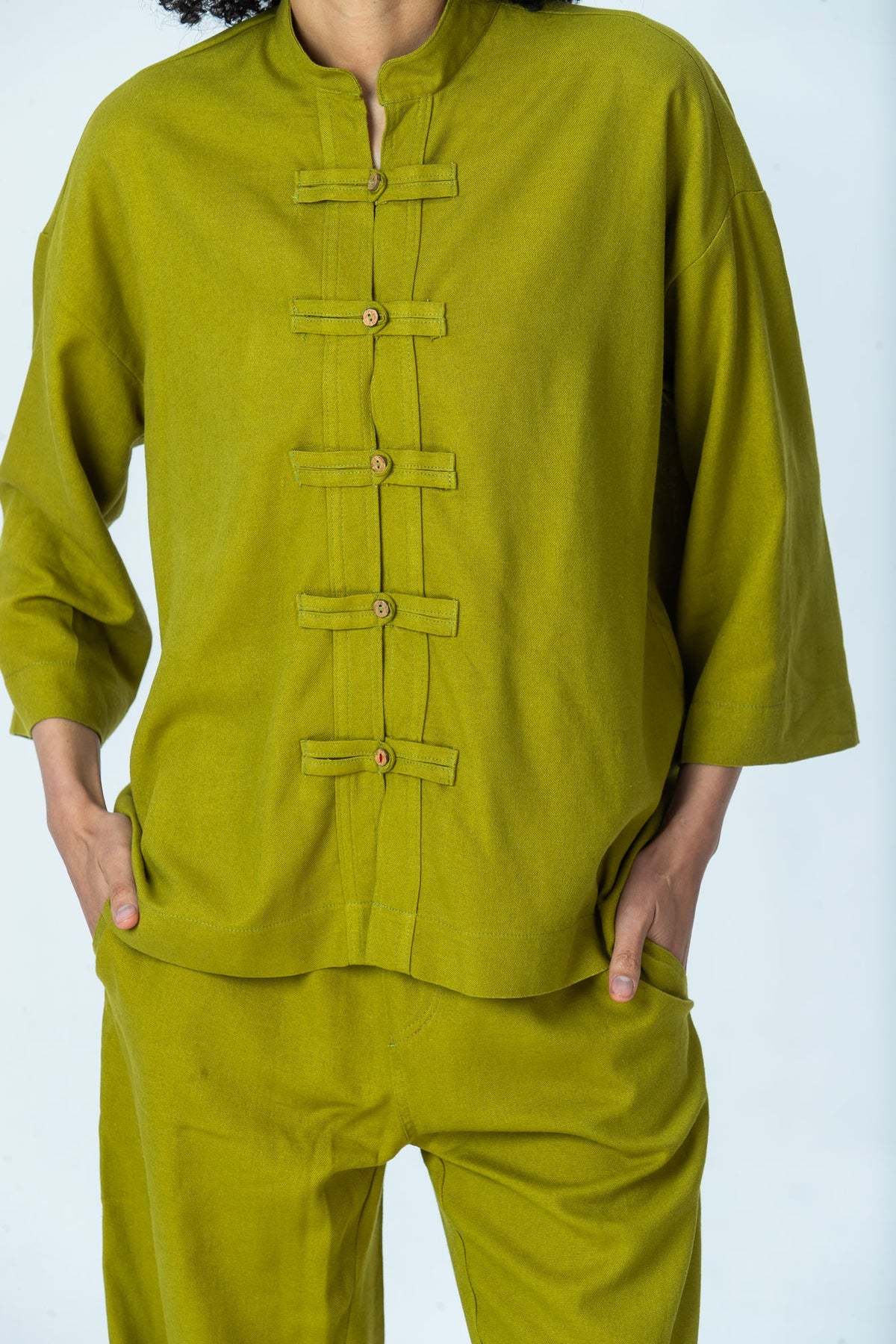 Kinsley chartreuse kaftan shirt, close up of frog fastenings and red thread on the final fastening