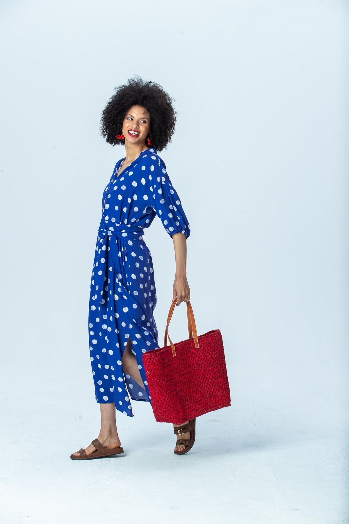 Sloane royal blue polka dot dress, side view full length walking, showing the side slit