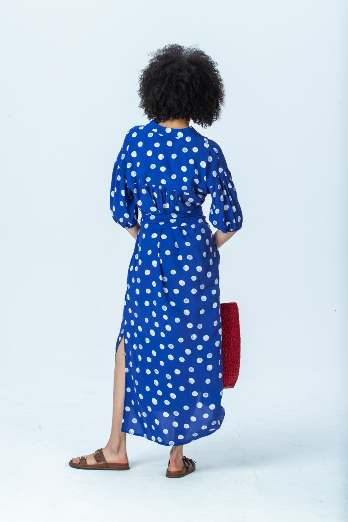 Sloane royal blue polka dot dress, back view full length showing the gathered back and side slit
