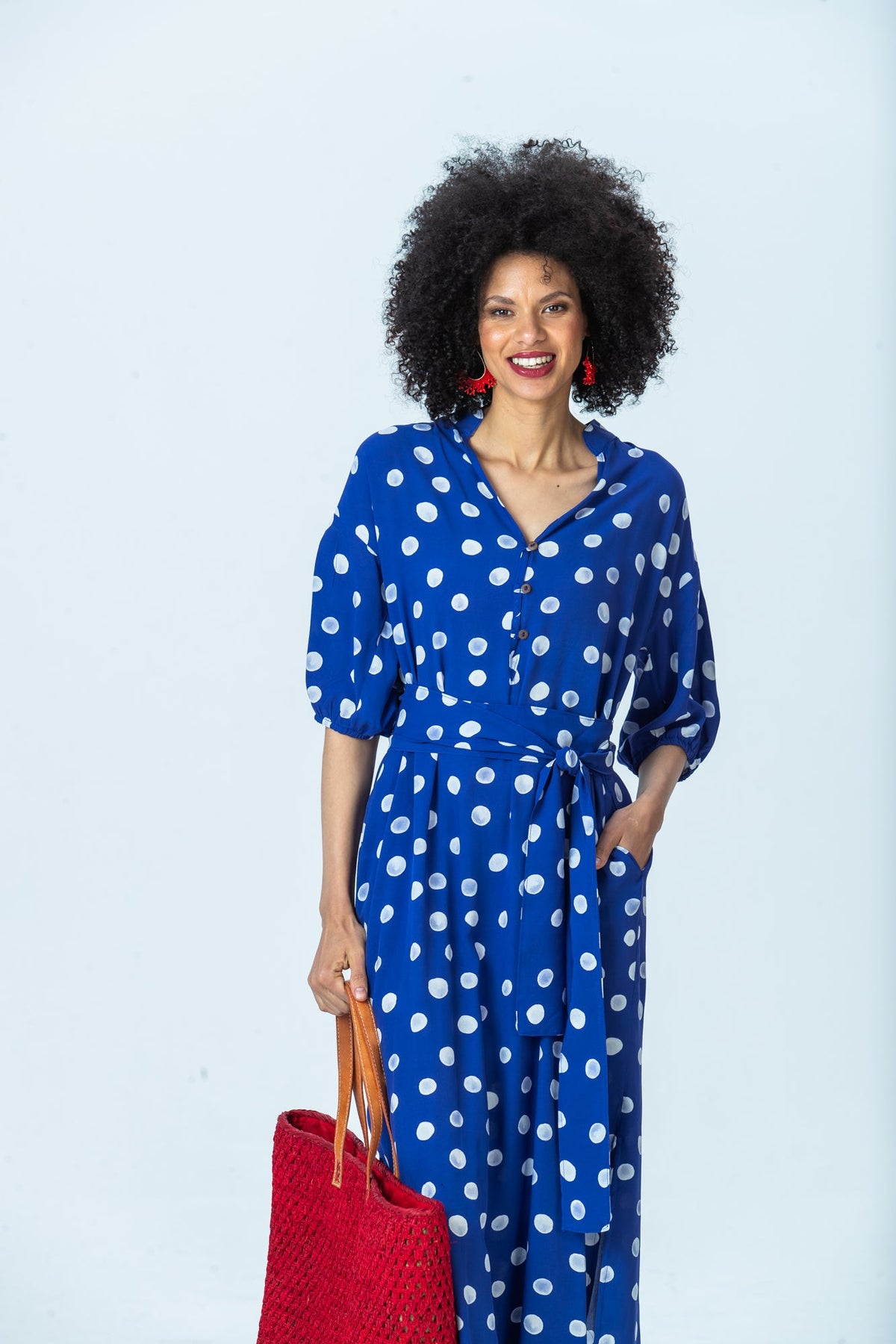 Sloane royal blue polka dot dress, front view, belted, hand in pocket