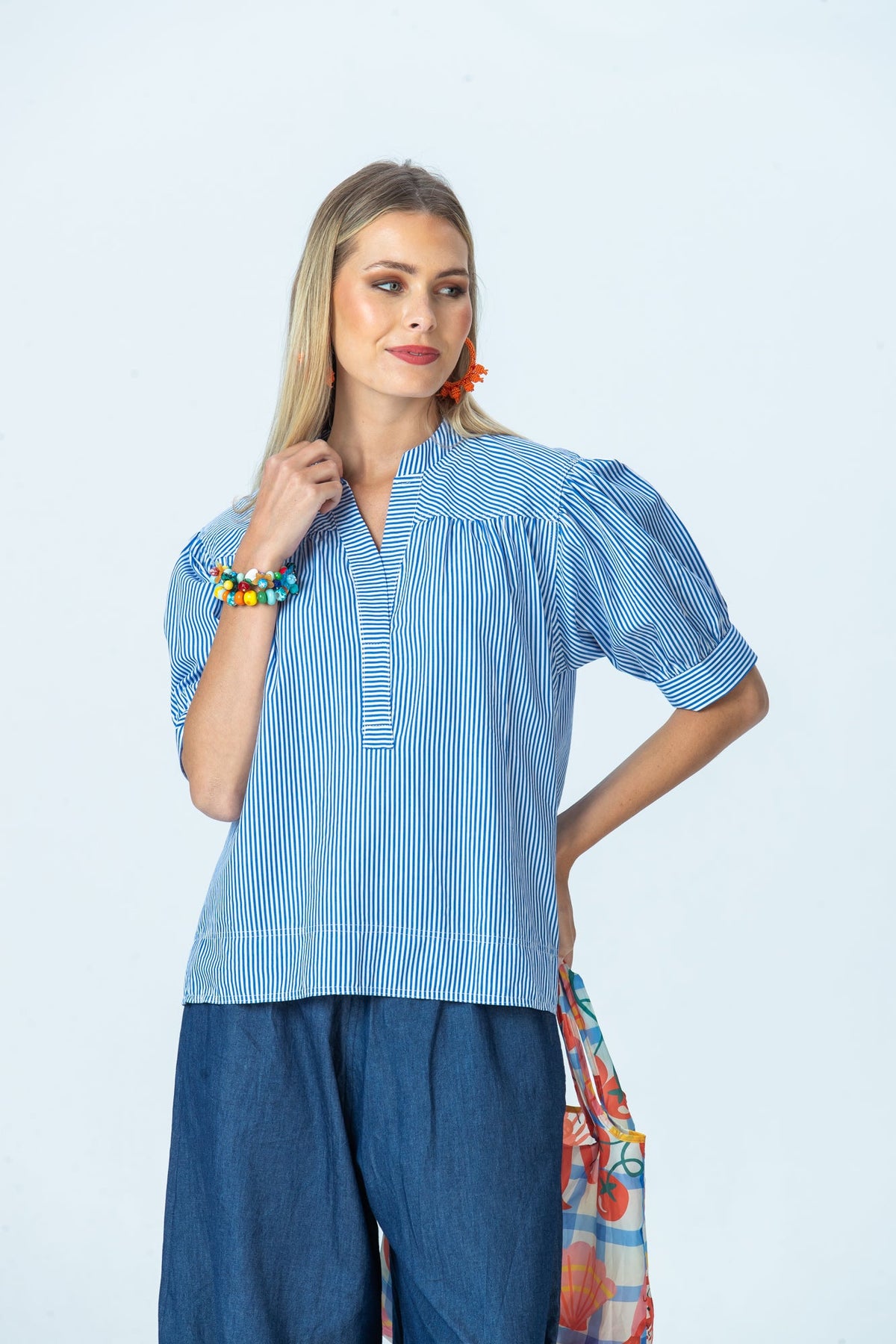 Tatum blue stripe shirt, front view with hand at collar, looking to the side