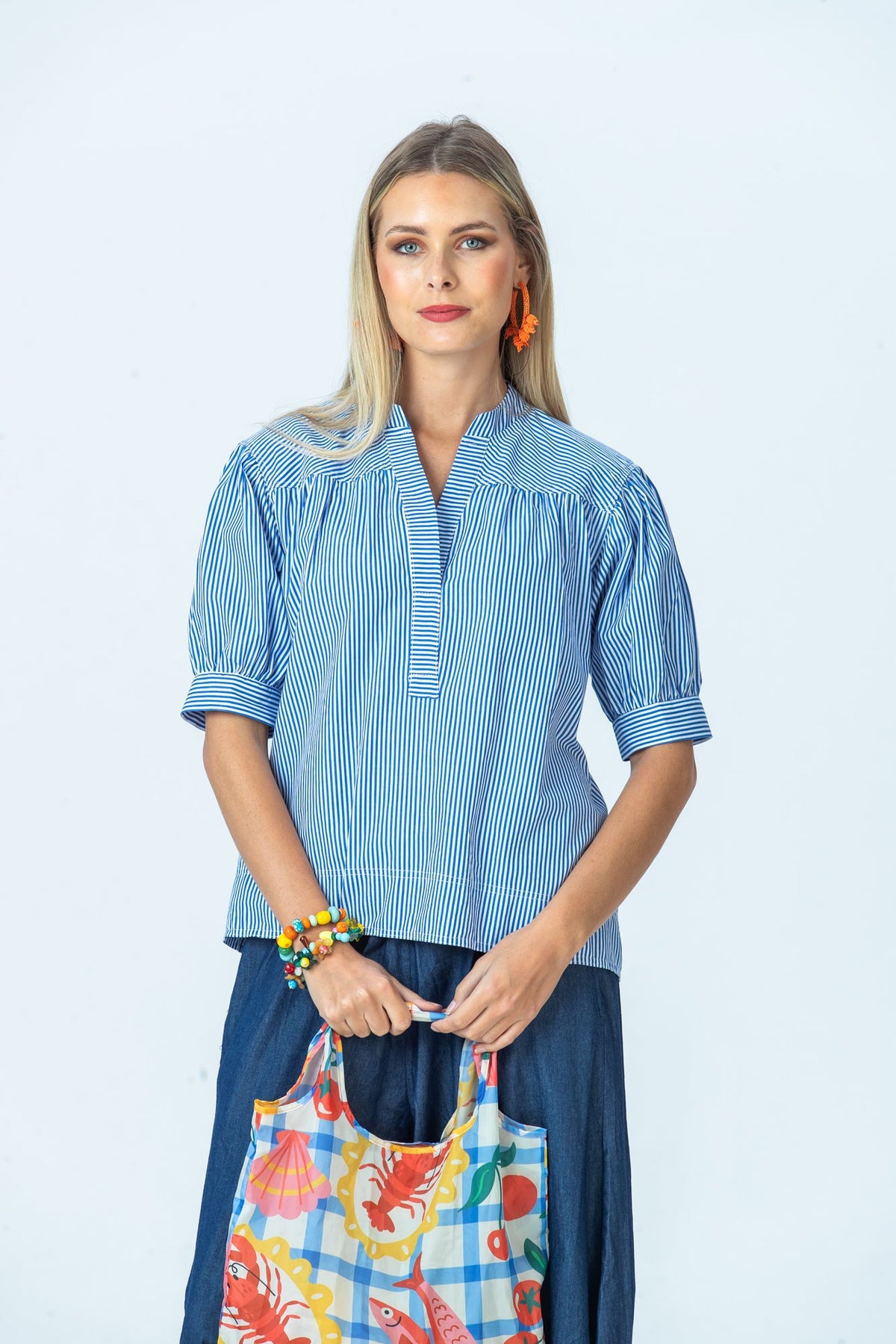 Tatum blue stripe shirt, front view holding a printed tote