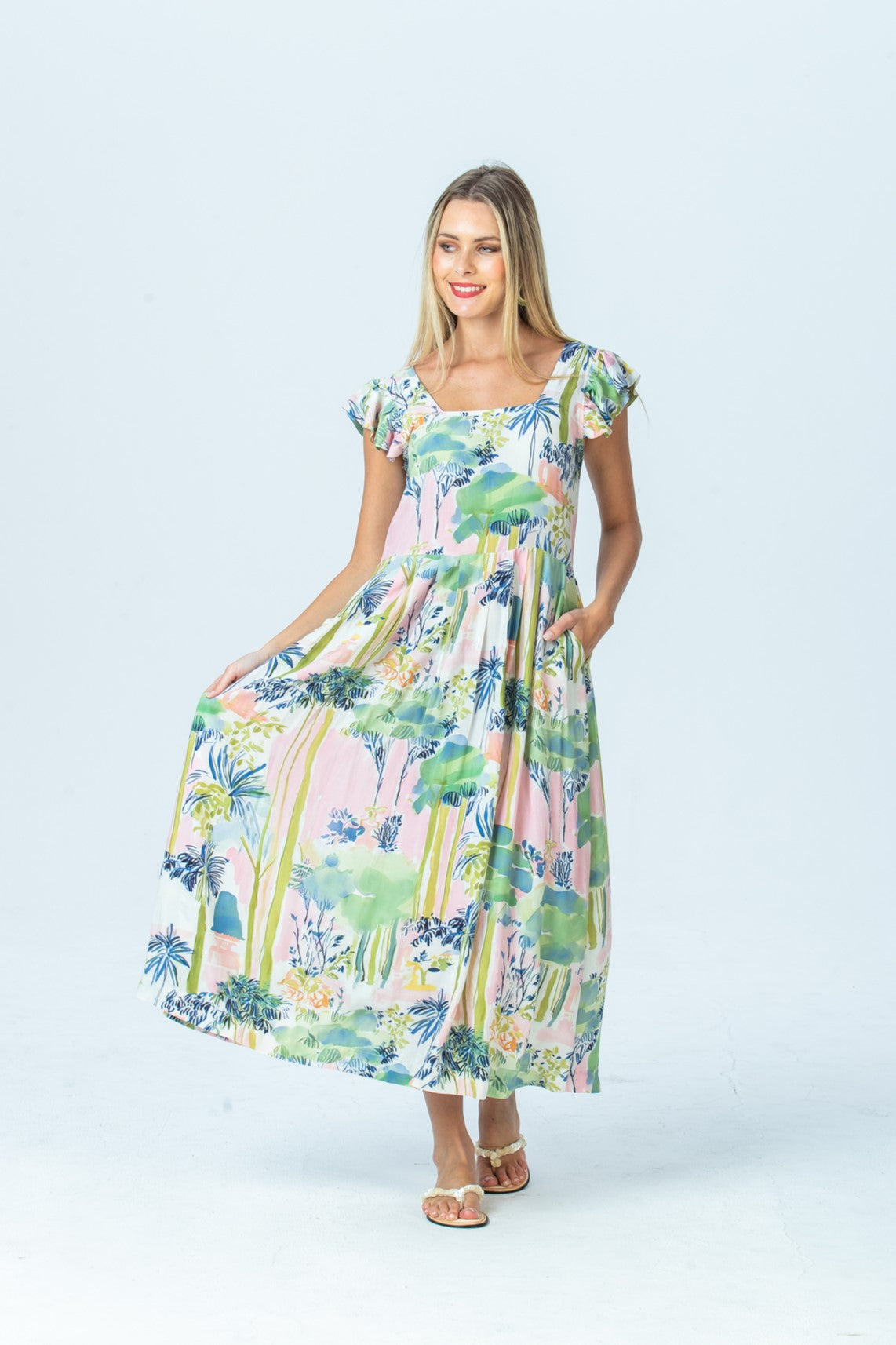 Sienna watercolour palm sundress, front view full length holding out the pleated skirt