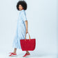 Frankie blue stripe shirt dress, side view full length walking with a red tote
