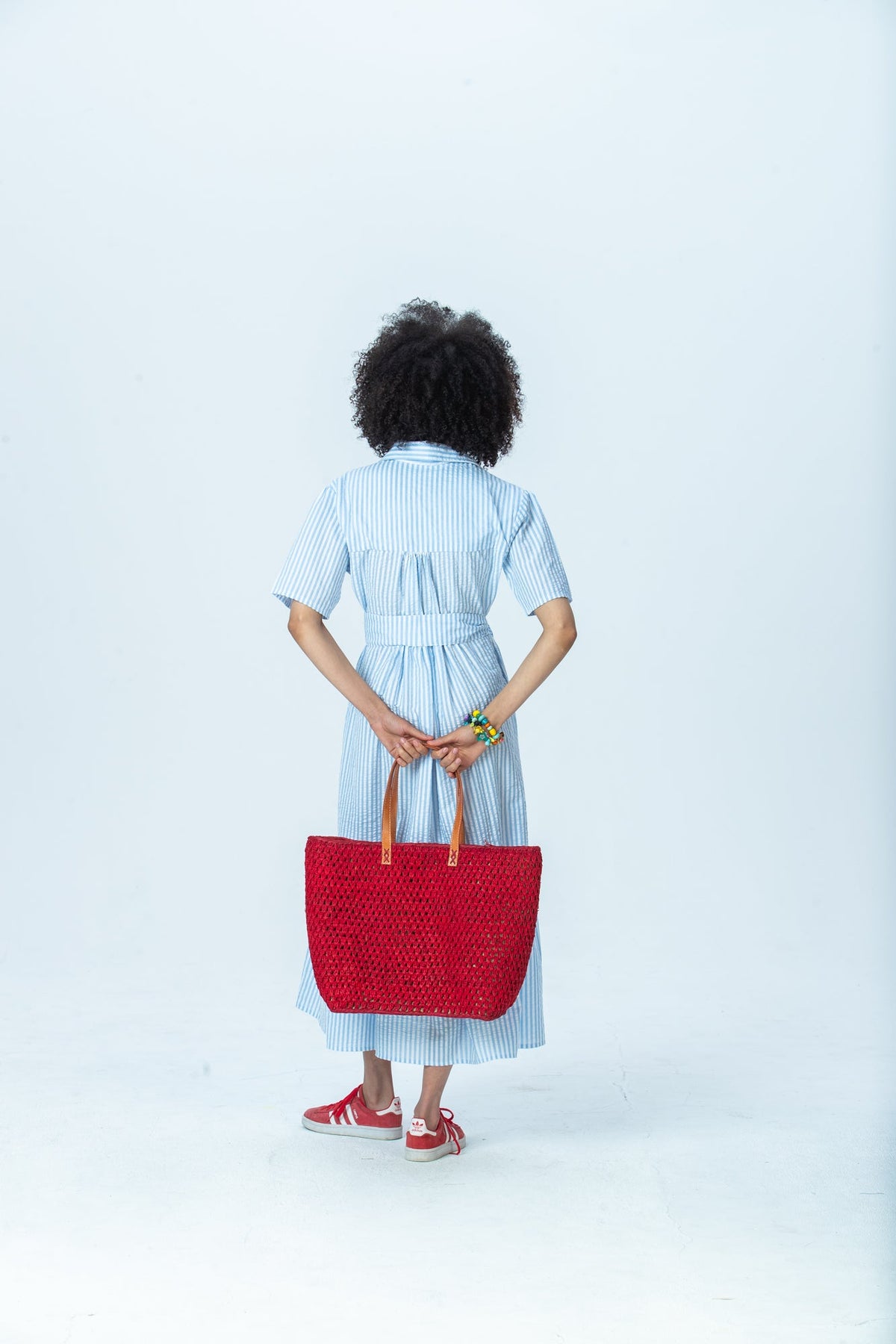 Frankie blue stripe shirt dress, back view full length holding a red tote behind her back
