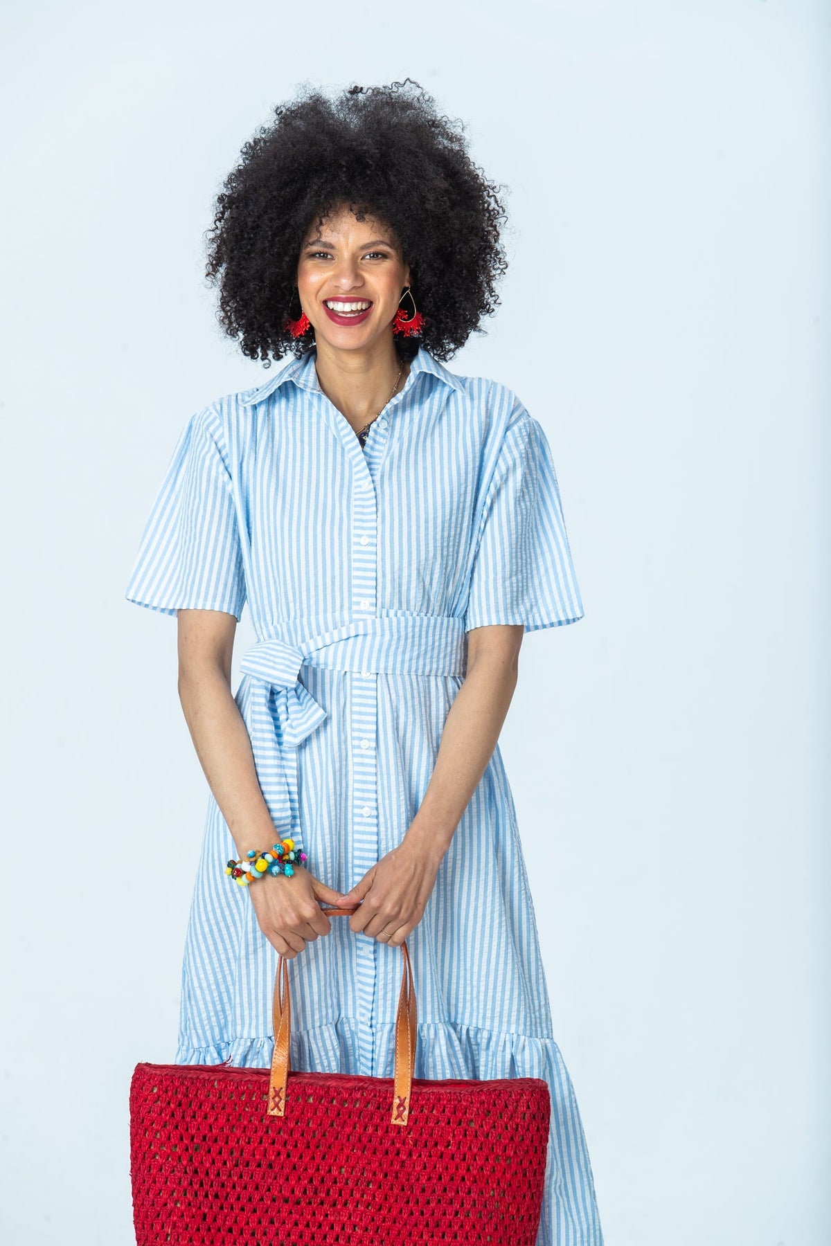 Frankie blue stripe shirt dress, front view holding a red tote with both hands
