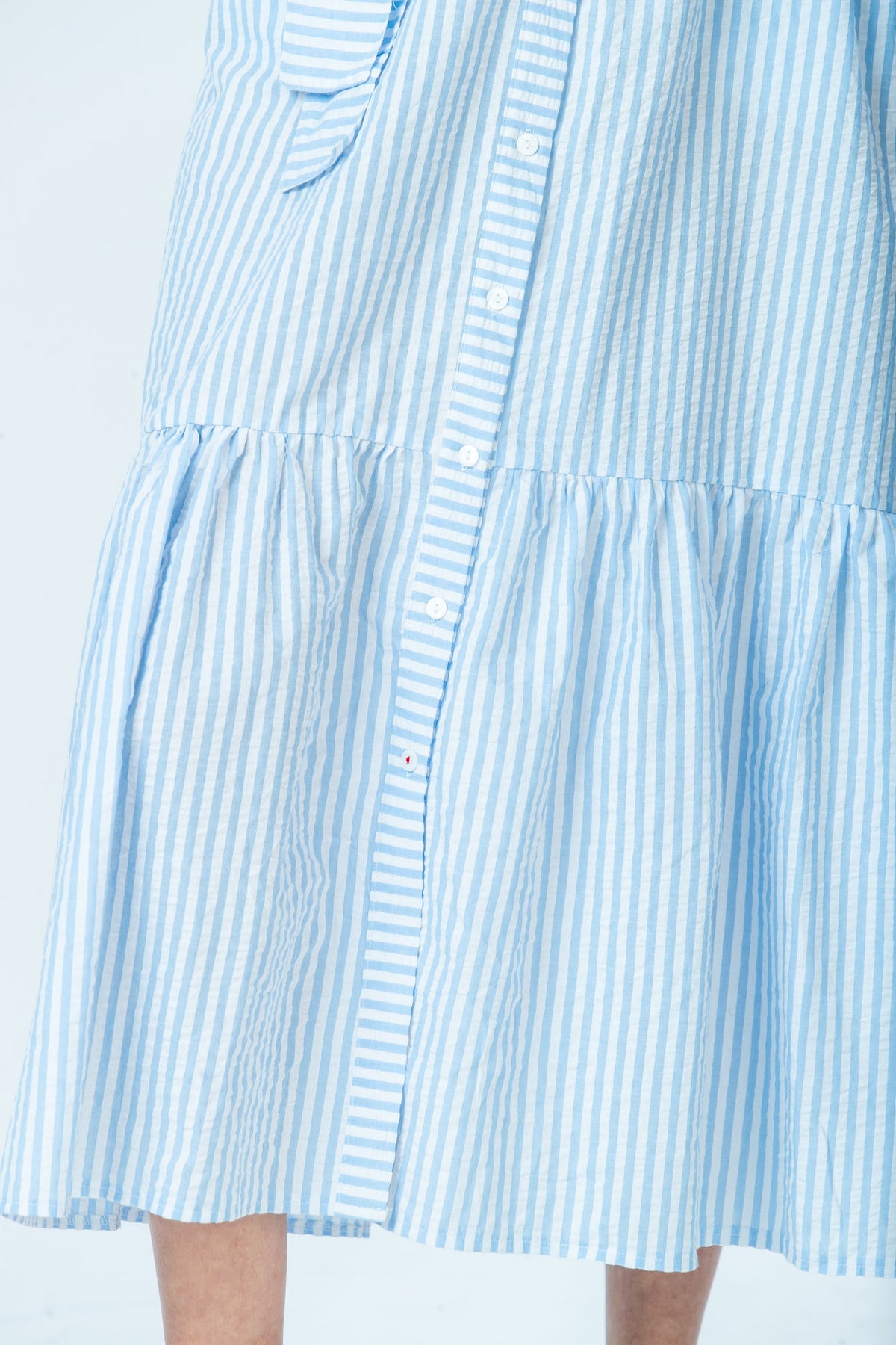 Frankie blue stripe shirt dress, close up of tiered hem and red thread button
