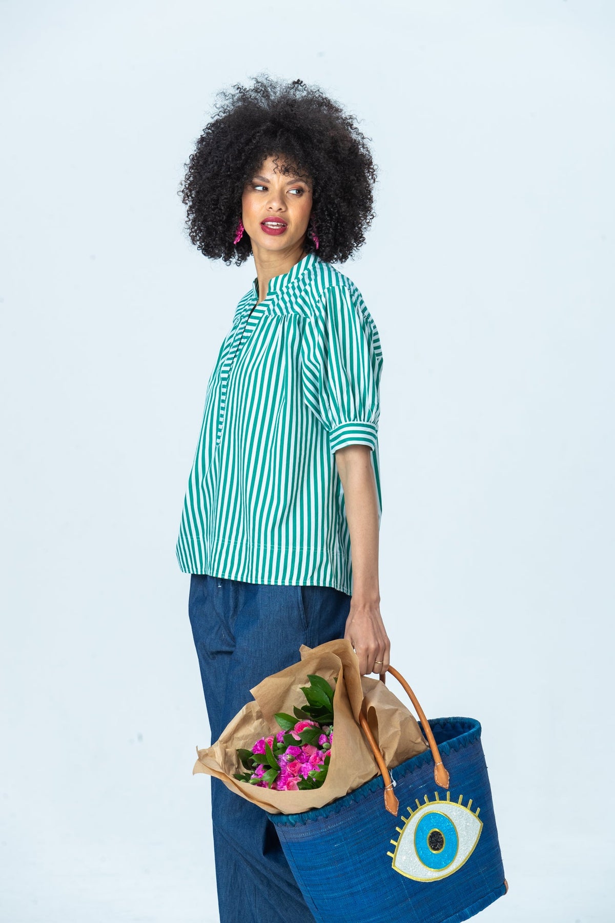 Tatum emerald stripe shirt, side view looking over the shoulder, carrying a woven basket
