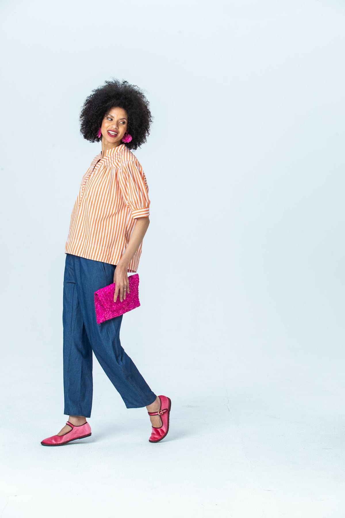 Tatum orange stripe shirt, side view full length walking, looking over the shoulder