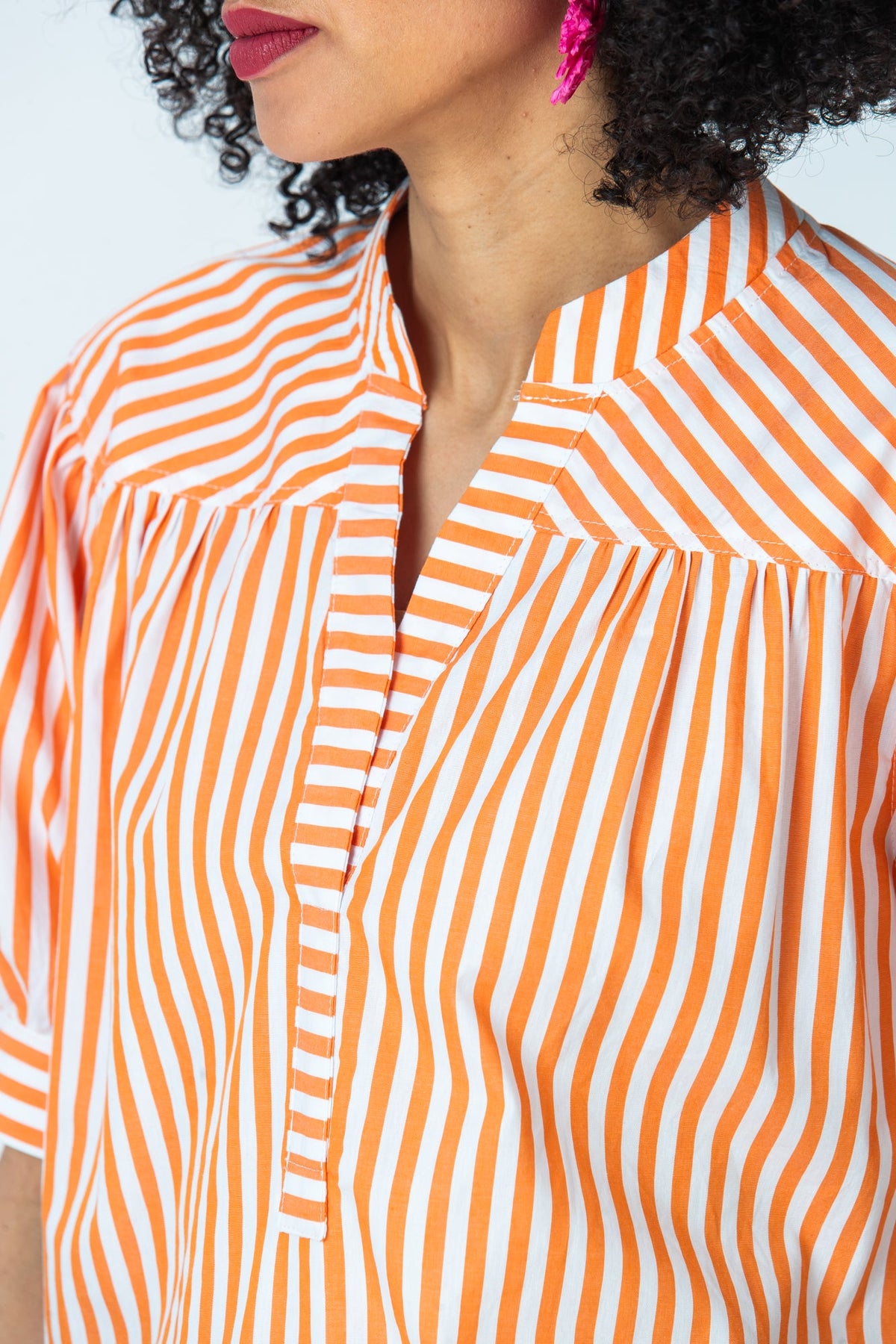 Tatum orange stripe shirt, angled close up of open V placket and gathered yoke