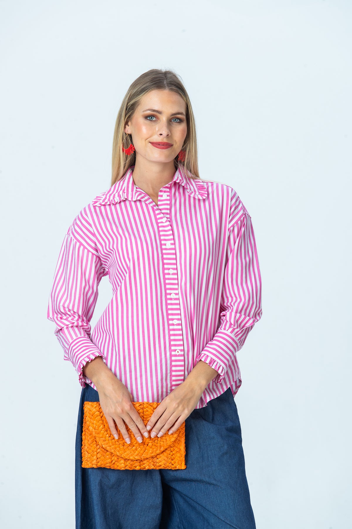 Claire pink stripe frill shirt, front view holding an orange woven clutch