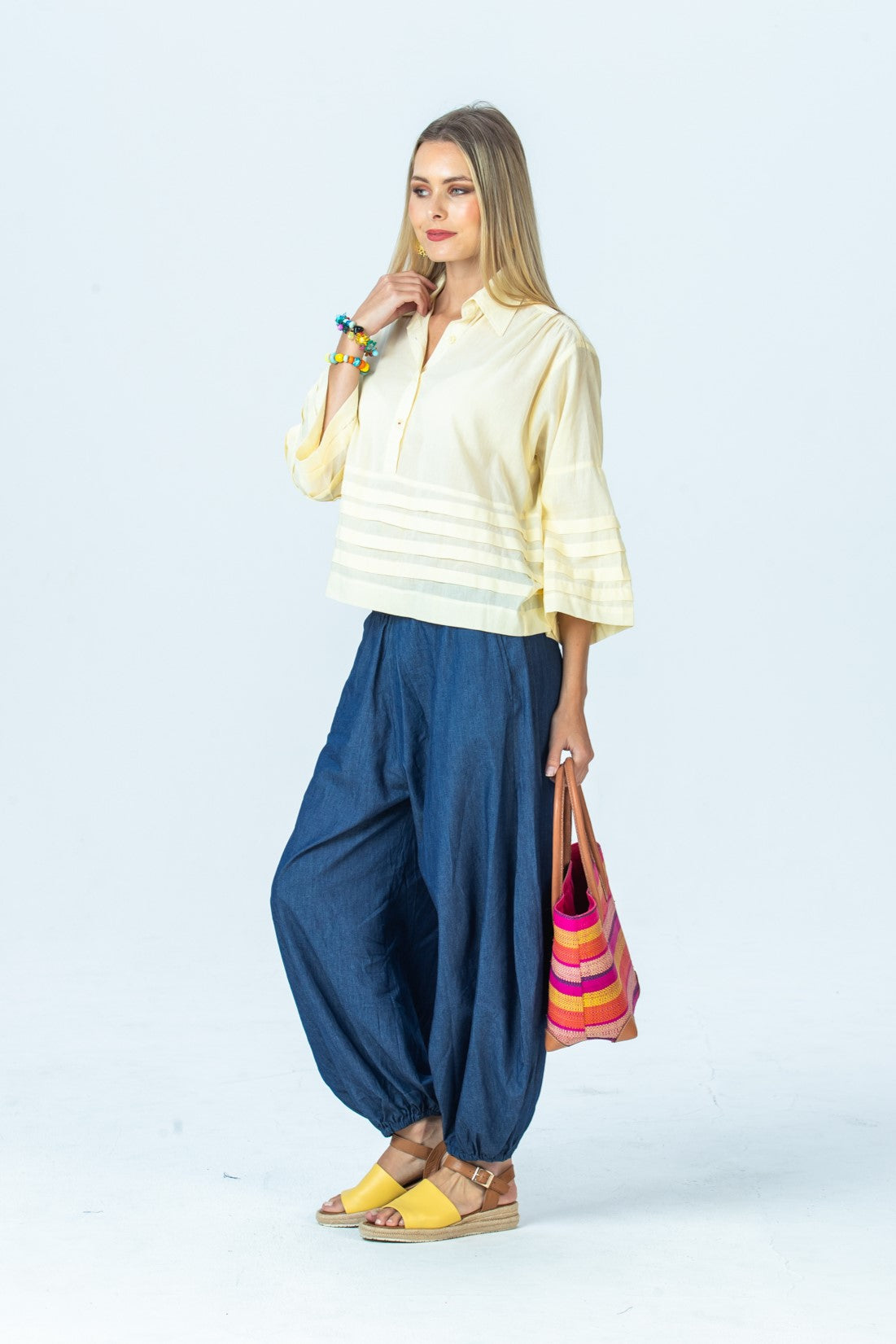 Serafina pale yellow shirt, side view full length with hand at collar