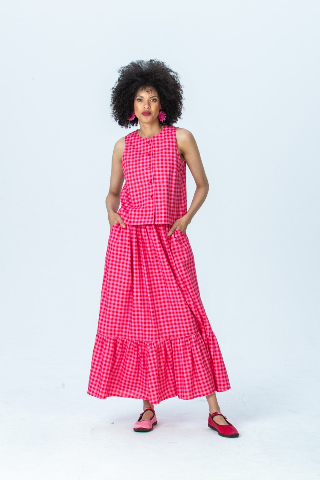 Riley red and pink check skirt, front view full length with hands in pockets, styled with the Brooke top
