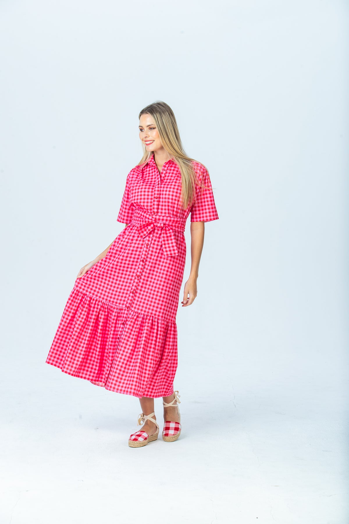 Frankie red and pink check shirt dress, three-quarter view holding out the tiered skirt