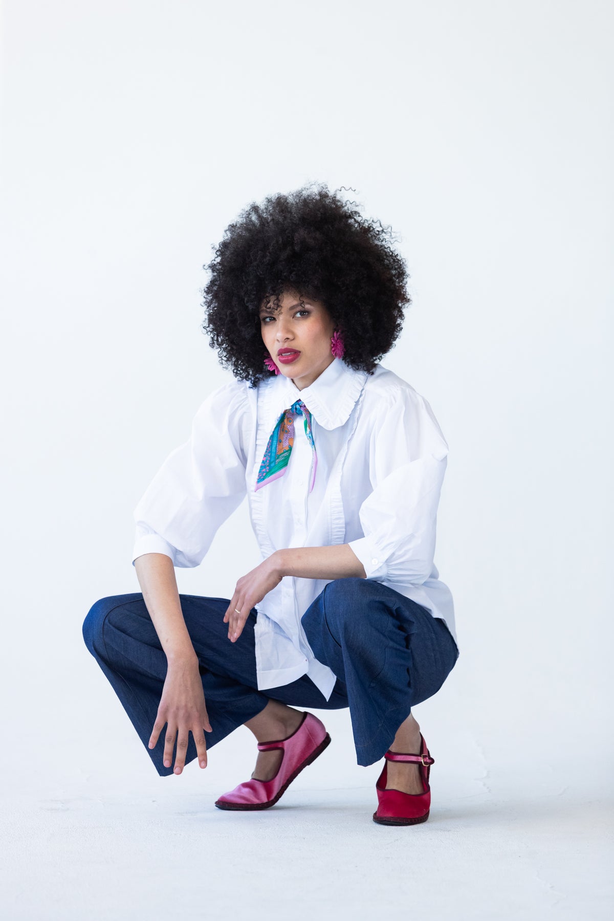 Claire frill shirt, crouching front view with neck scarf and wide-leg denim pants
