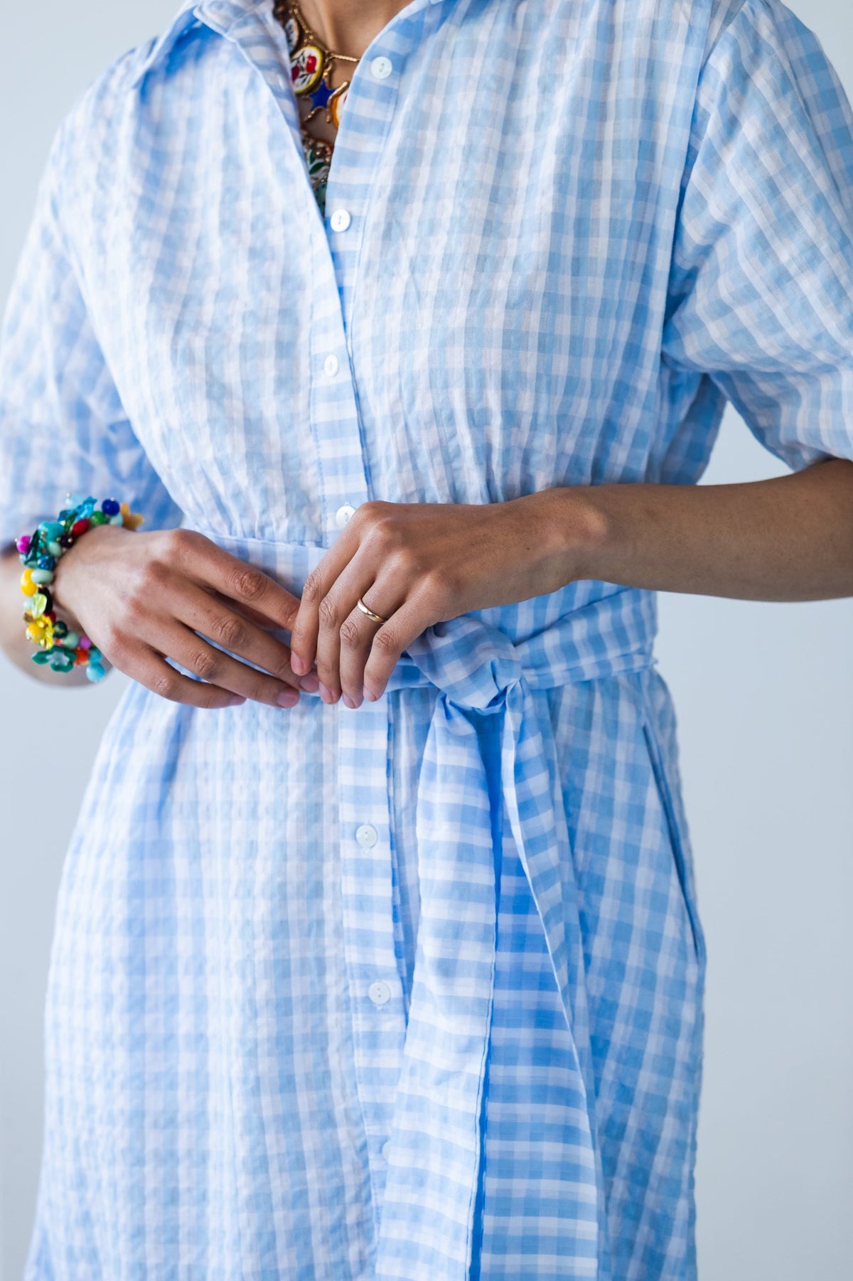 Frankie blue check dress, close-up of tied belt and hands at waist