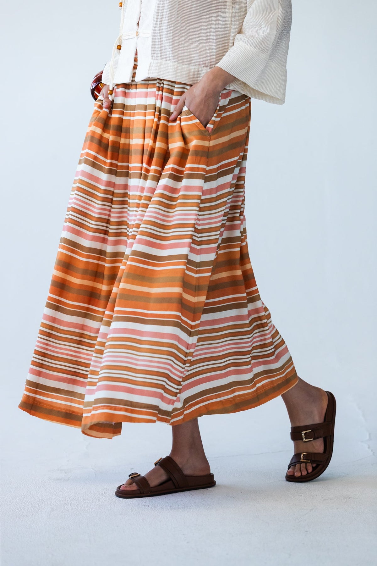 Sorrento Sunset Stripe skirt, close-up side view showing pleats and pocket