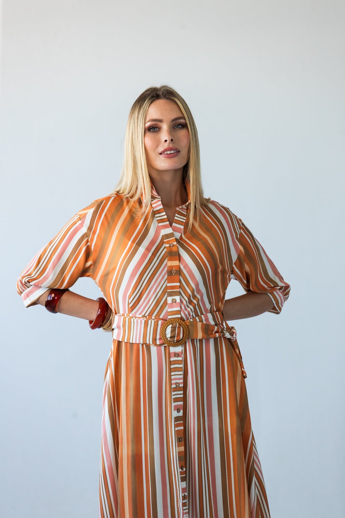 Cassidy Sunset Stripe dress, close-up front view with hands on hips, belt buckle visible