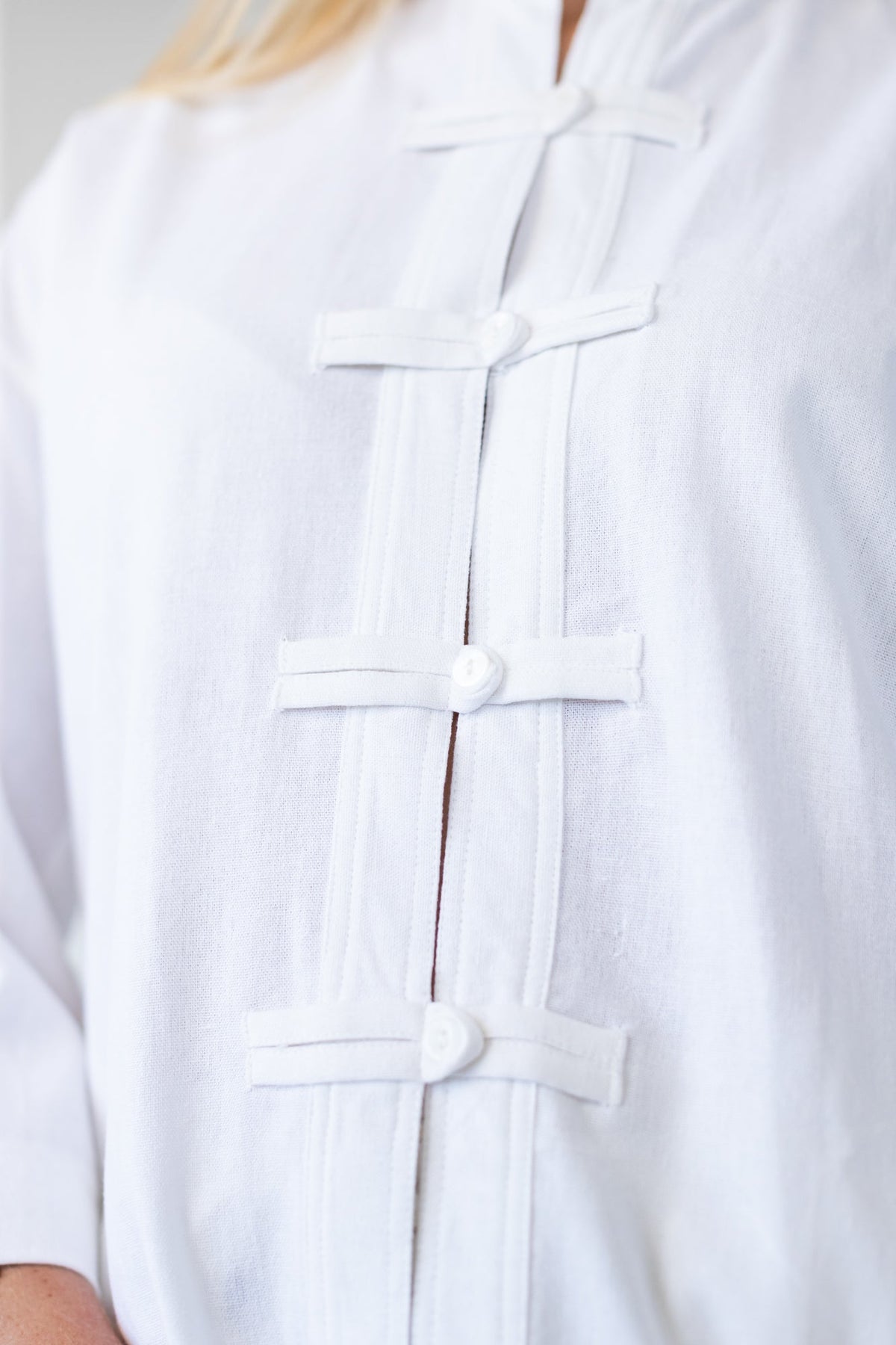 Kinsley white kaftan-style shirt, close up detail of frog fastening