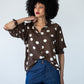 Harper polka dot shirt, front view with one hand at the collar showing the balloon sleeves