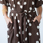 Sloane polka dot dress, close up of belt tie with hands in pockets