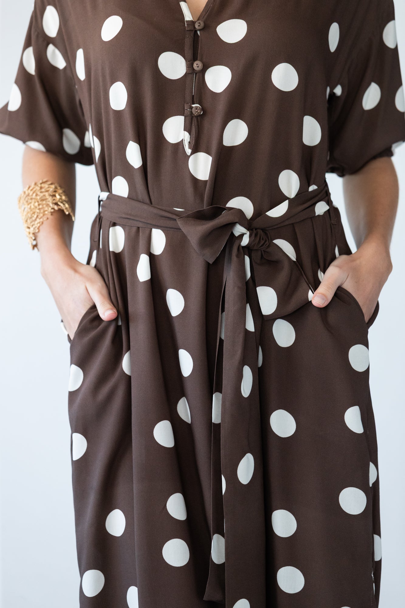 Sloane polka dot dress, close up of belt tie with hands in pockets