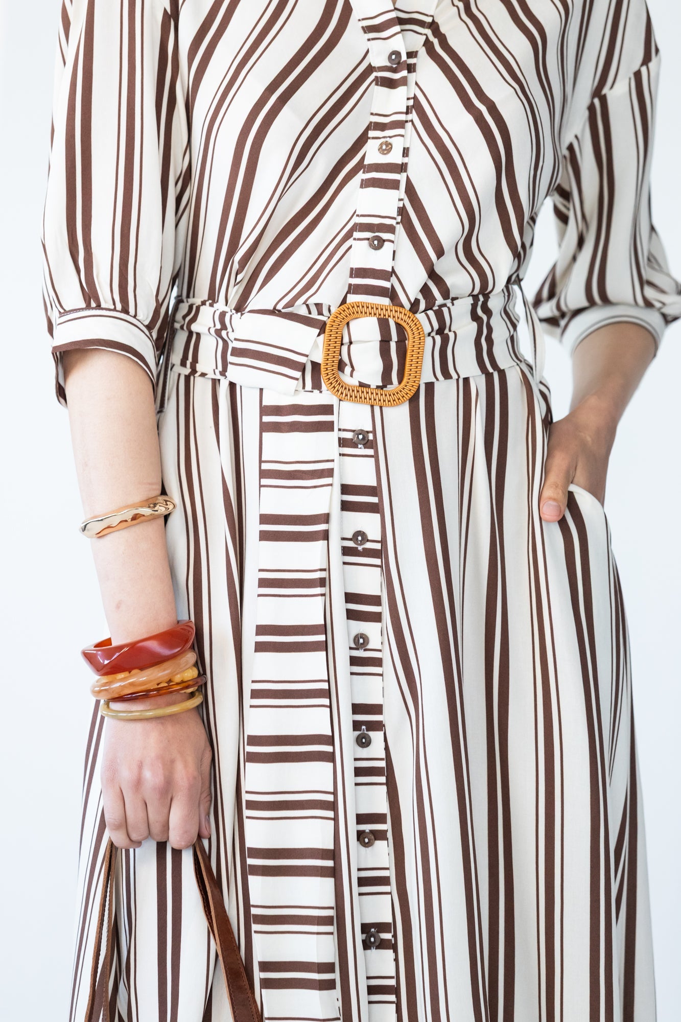 Cassidy stripe dress, close up of button stand and belt buckle and hand in pocket