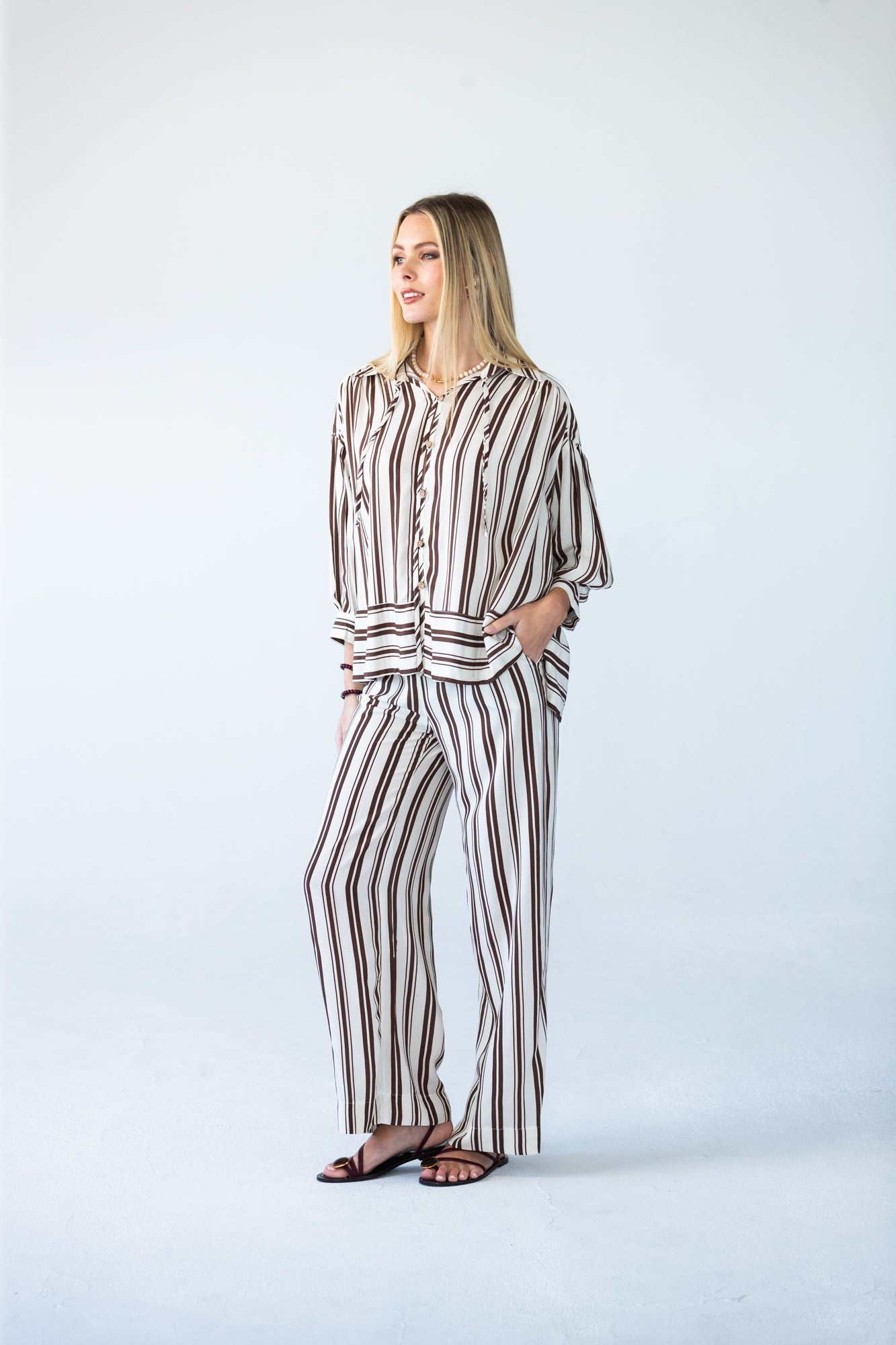 Sydney chocolate stripe wide leg pants, front view looking to the side with hand in pocket