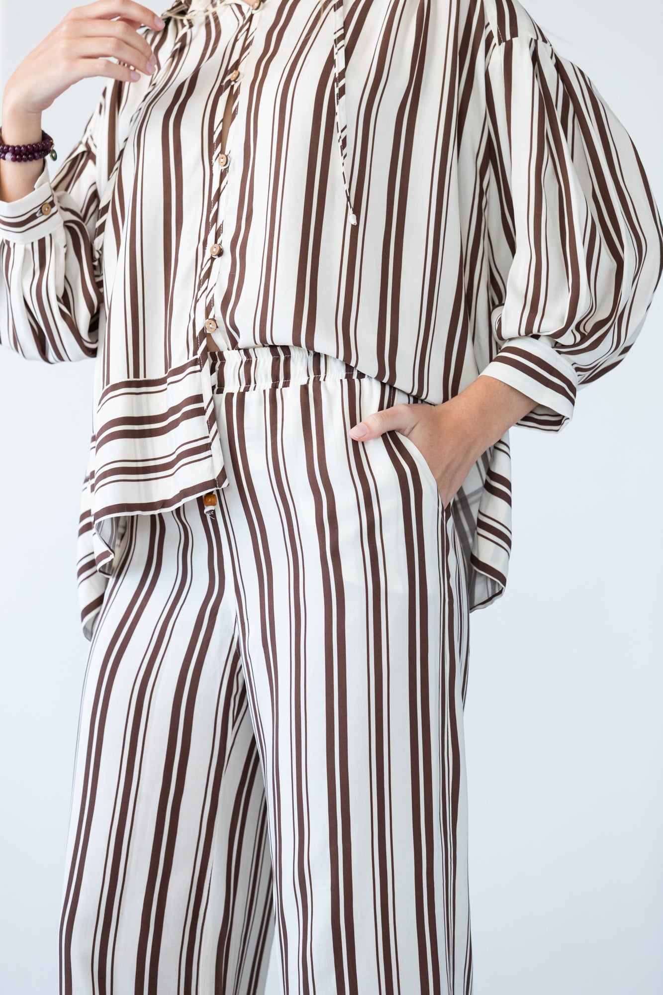 Sydney chocolate stripe wide leg pants, close up front view with hand in pocket