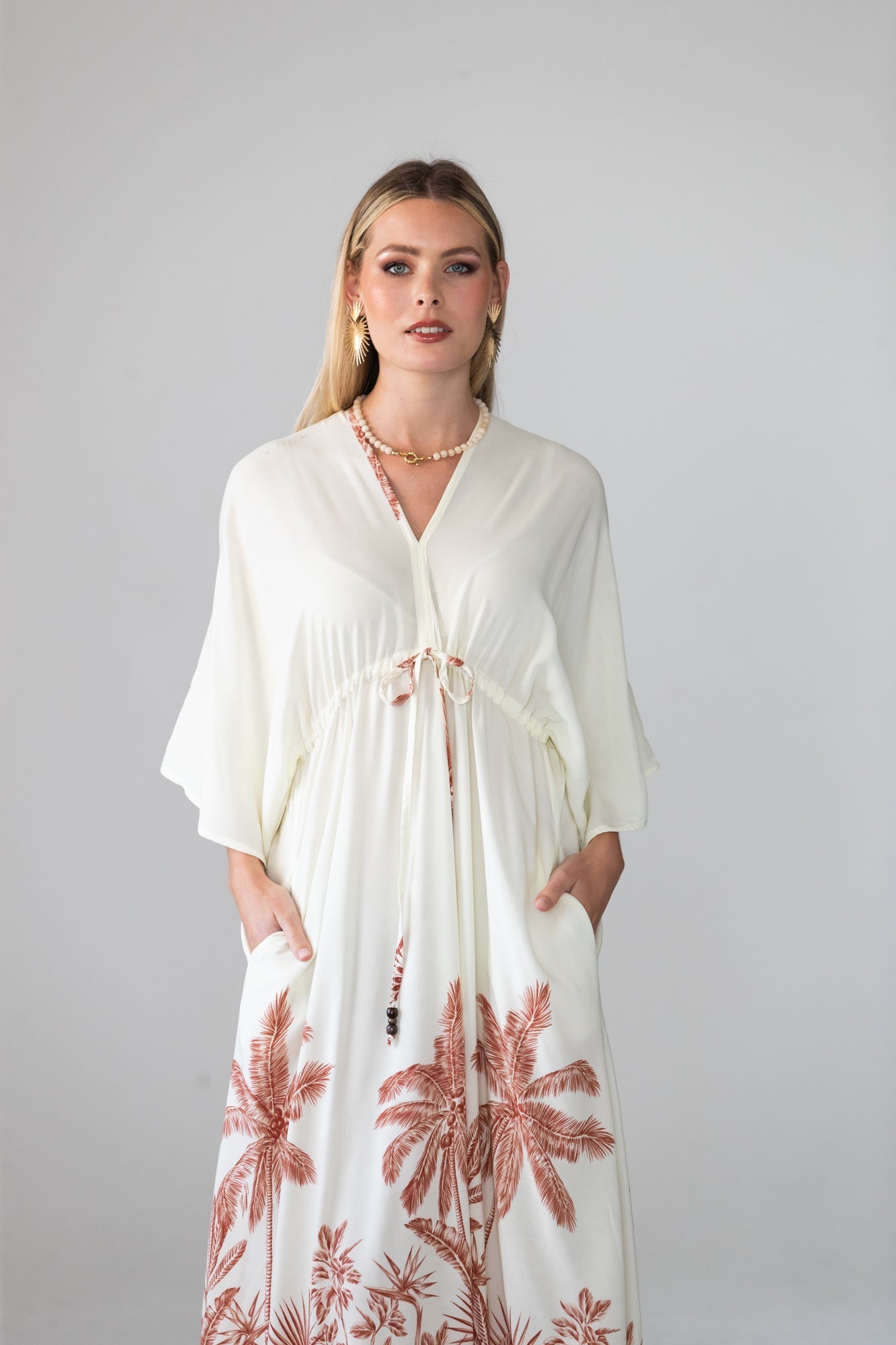 Georgia cream palm print kaftan, close up of neckline with hand at chest