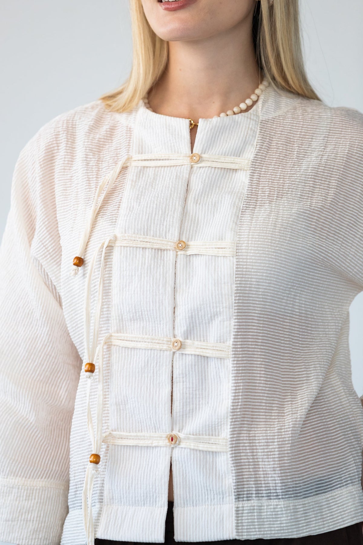 Amelia milk relaxed shirt, close up of neckline and toggle closures, smiling