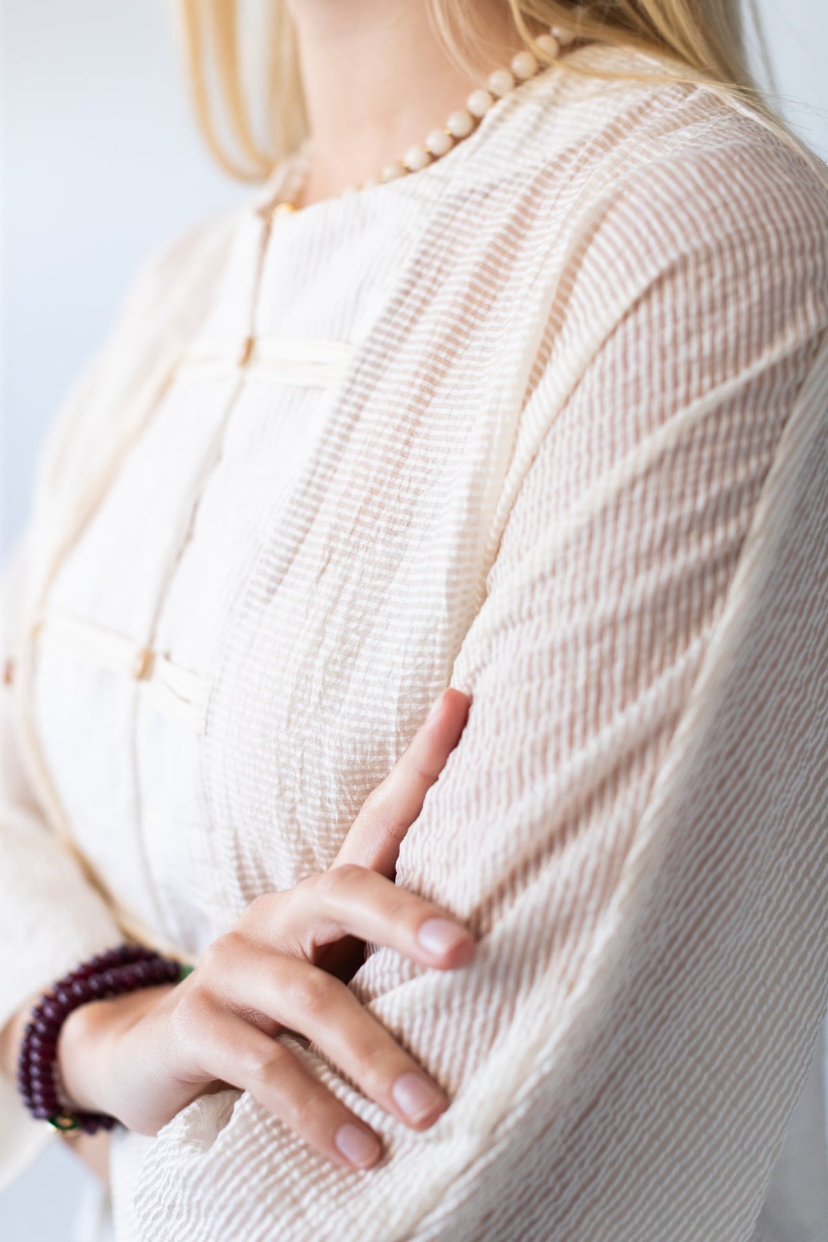 Amelia milk relaxed shirt, close up of batwing sleeve with hand adjusting collar
