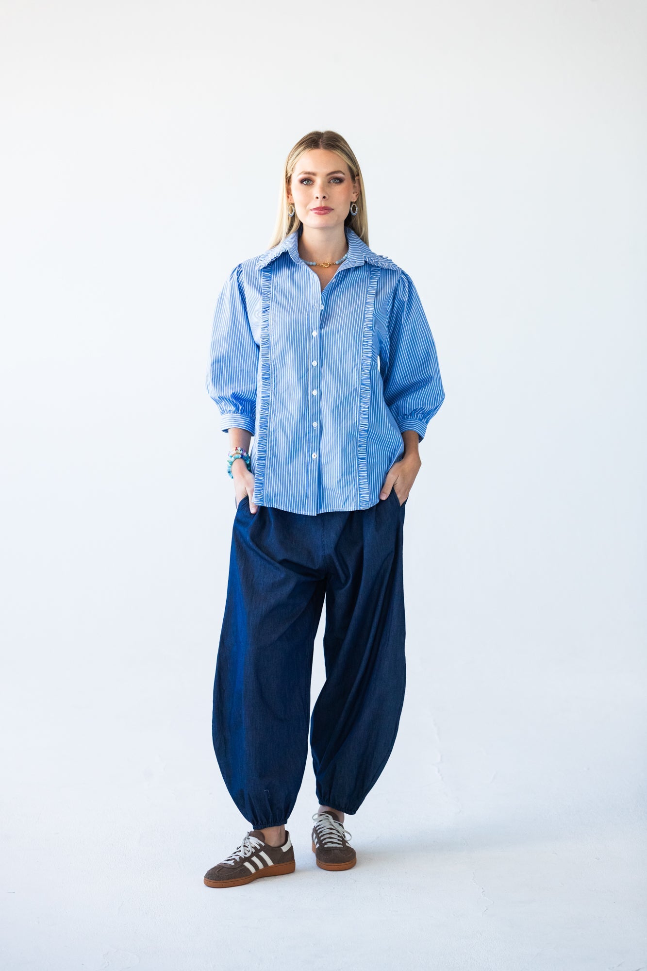 Claire blue and white stripe shirt, front view styled with balloon pants and sneakers