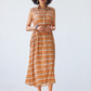 Sutton sleeveless shirt-dress in orange check, full-length front view with hands clasped
